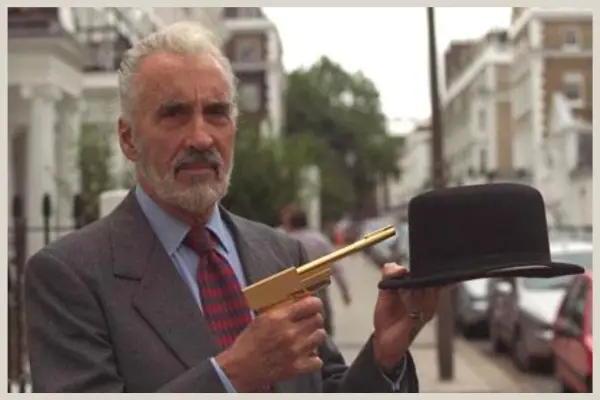 Christopher Lee posing with the golden gun and Nick Nack's bowler hat